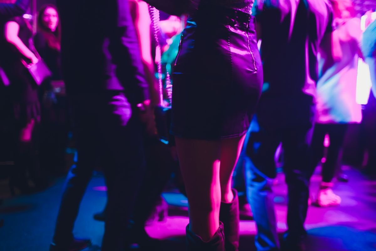 Ambiance nocturne d'un club privé bruxellois, lumières chaudes et silhouettes élégantes