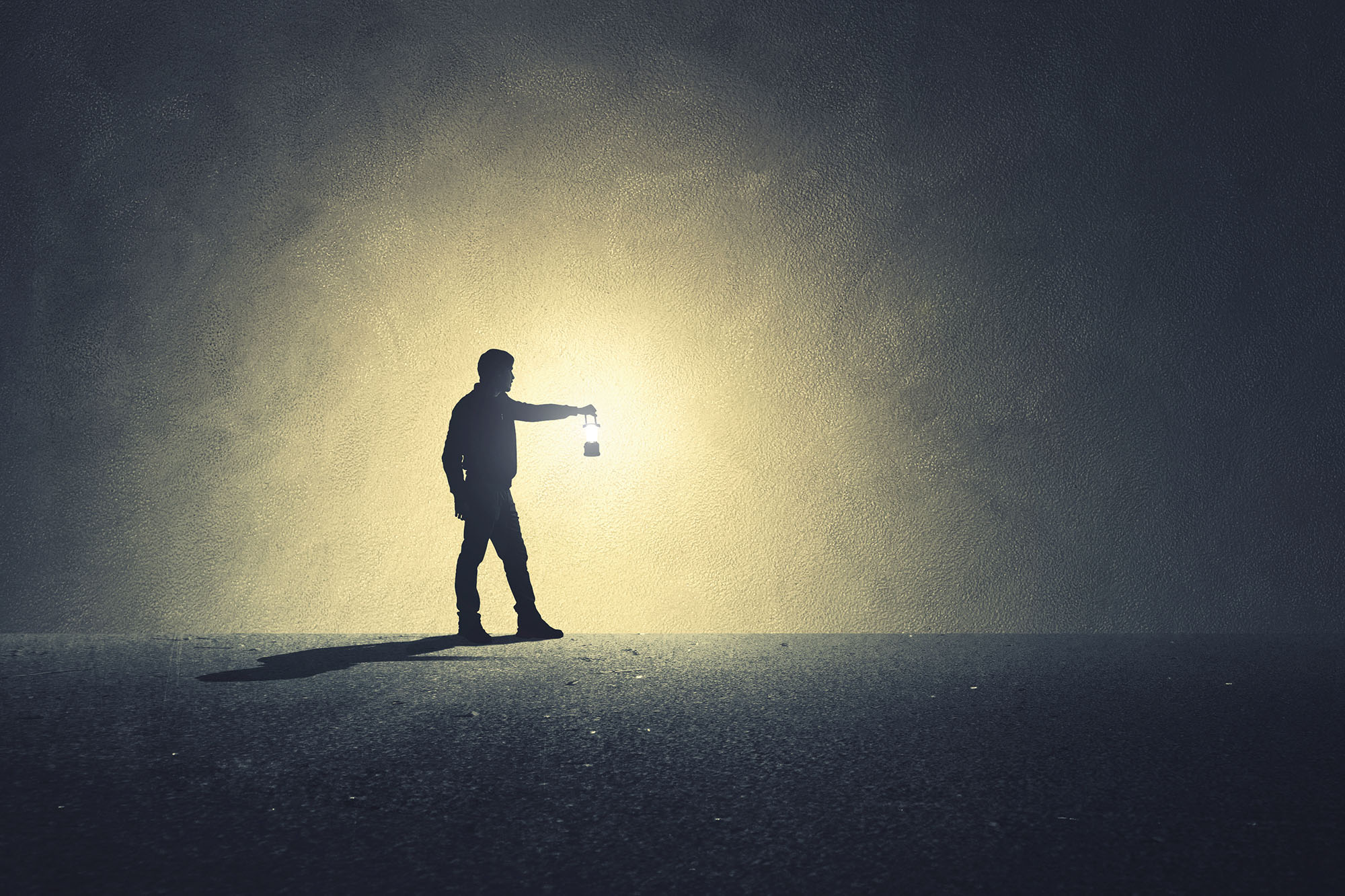 Silhouette d'une personne qui avance avec une lanterne dans la pénombre, métaphore d'un parcours guidé vers la découverte