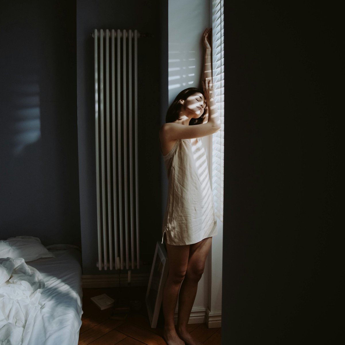 Femme en nuisette à la fenêtre, lumière matinale tamisée — communauté féminine Velvexx